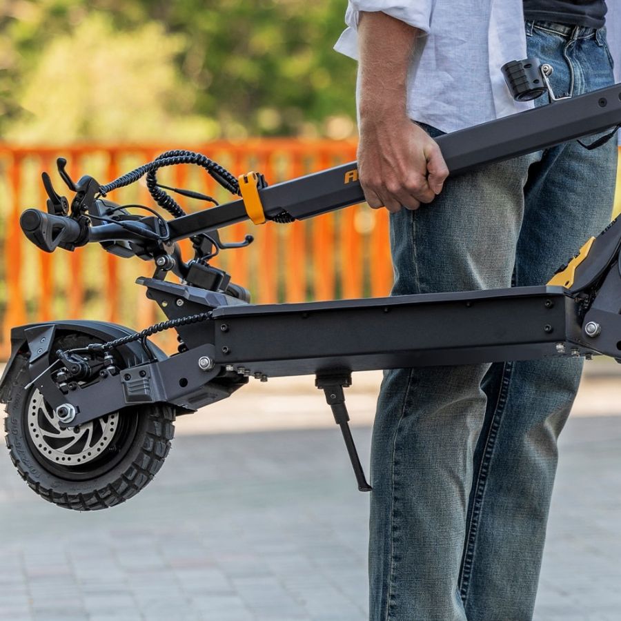 Person holding a folded electric scooter with a blurred background L1_Electric_scooter_Folded_carring_by_person