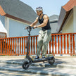 Person riding an electric scooter on a rooftop with a clear sky Person_riding_the_L1_Ausom_Electric_scooter_2