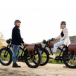 Two people standing next to electric bikes in a natural setting Cheetah Pro Sale Revi Ebike