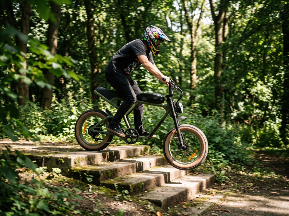 A person riding a black electric mountain bike with fat tires down a set of stone steps in a dense green forest. Back to modern Revi e-bikes 