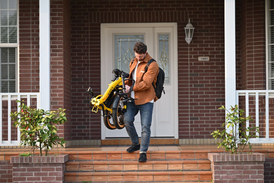 Rider carrying the folded Revi Rebel 2 electric bike, folded size 34.7 by 27.6 by 11.8 inches