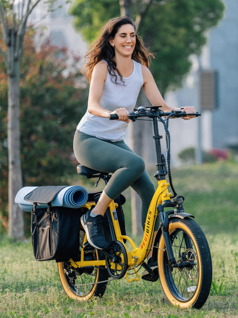 Woman riding the Revi Rebel 2 folding e-bike with loaded rear saddle bags