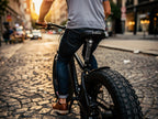 Rider crossing rough cobblestones on a fat tire e-bike with the ZOOM shock-absorbing seatpost compressing under the saddle